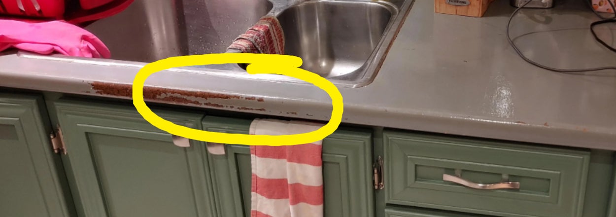Close-up of a kitchen sink area with a visible edge chipped off from the countertop