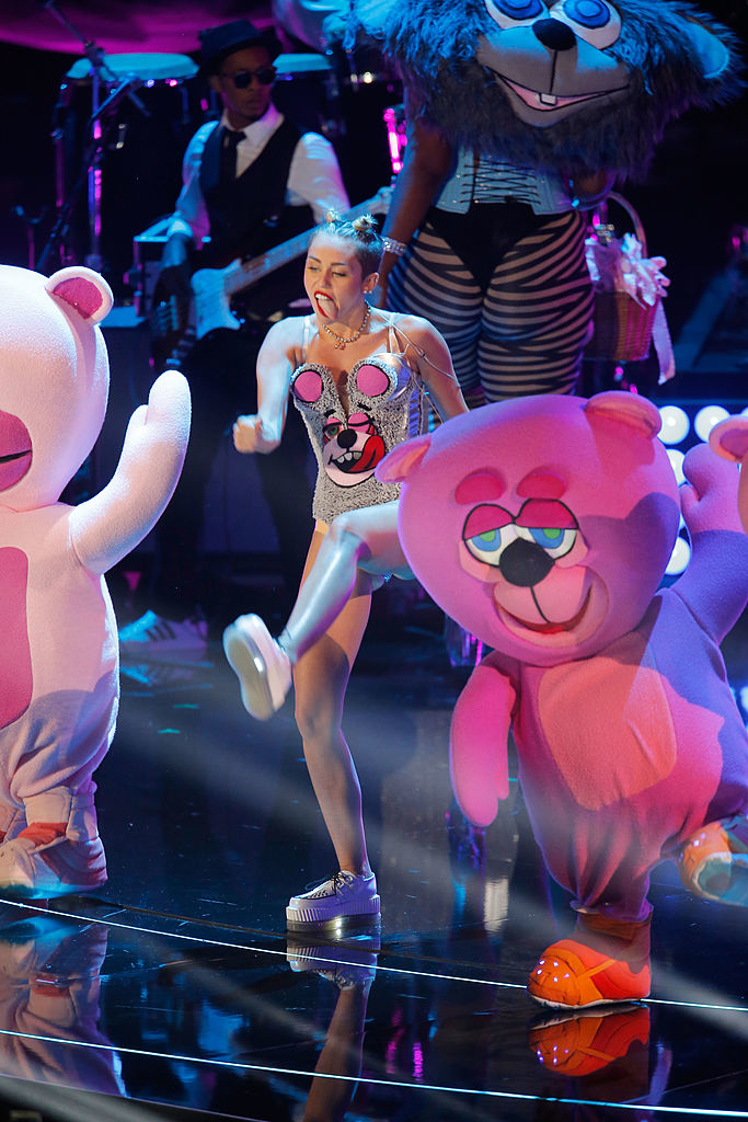 Miley Cyrus performing on stage with dancers in bear costumes