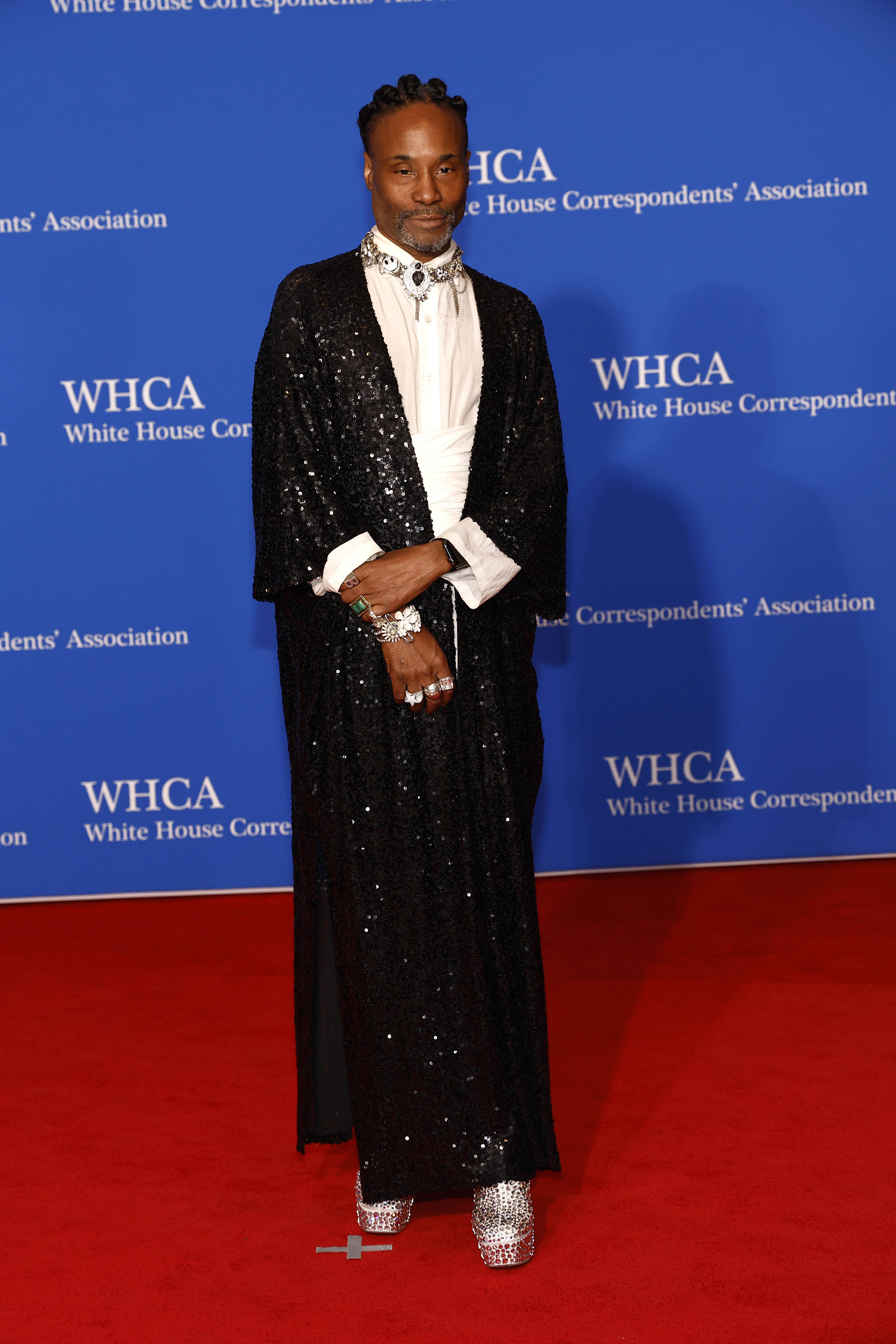 Billy Porter in a sparkling black outfit with a white scarf and glittering shoes at the WHCA event