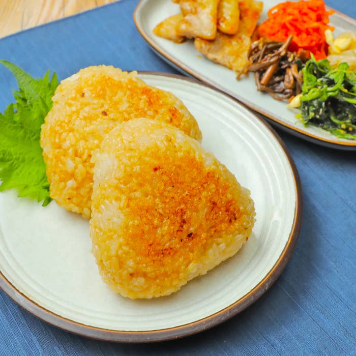 おにぎり2つが皿に盛られ、添え物として野菜がある。