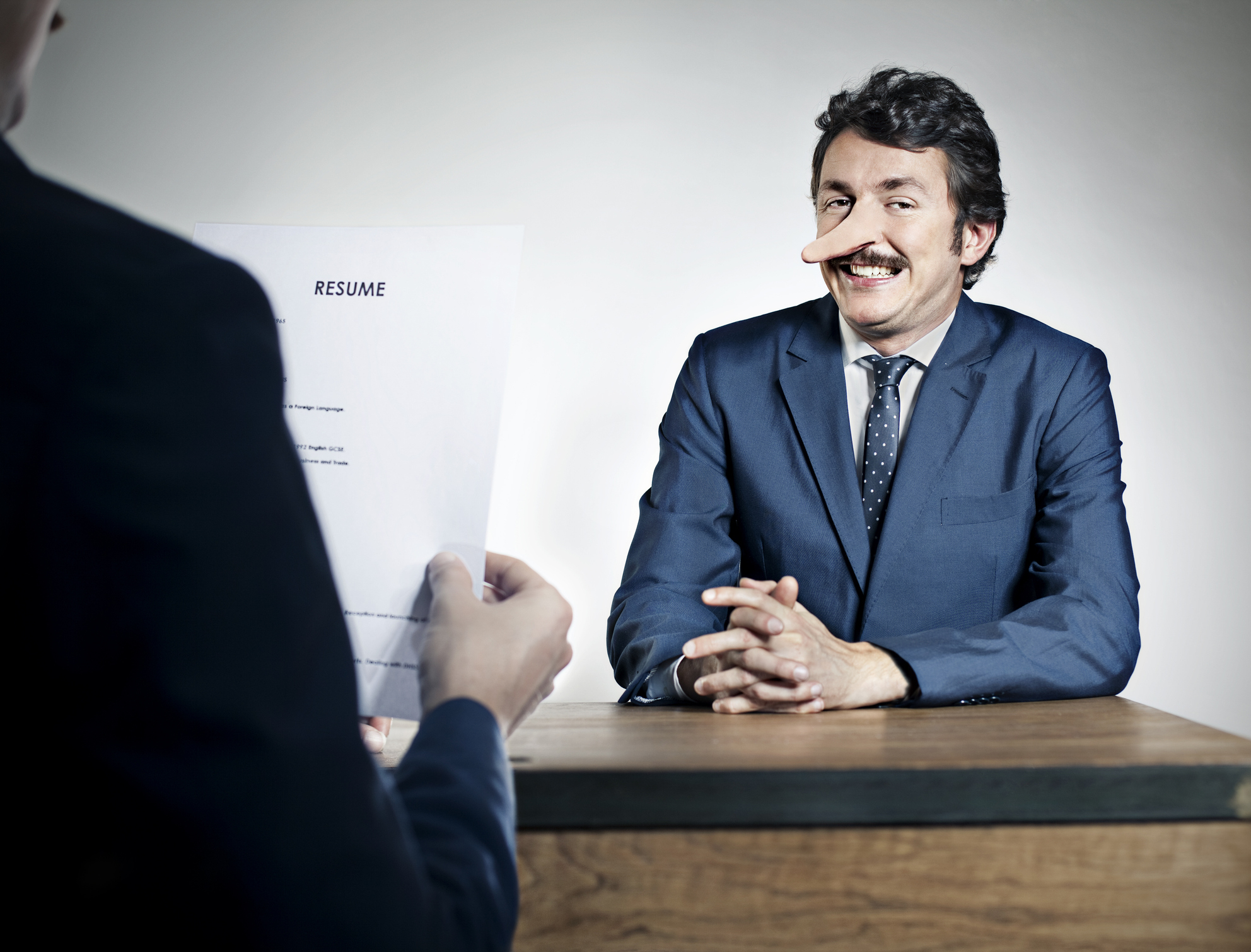 Person with a pen in nose smiles during a job interview, likely humor related to the &quot;Tasty&quot; category