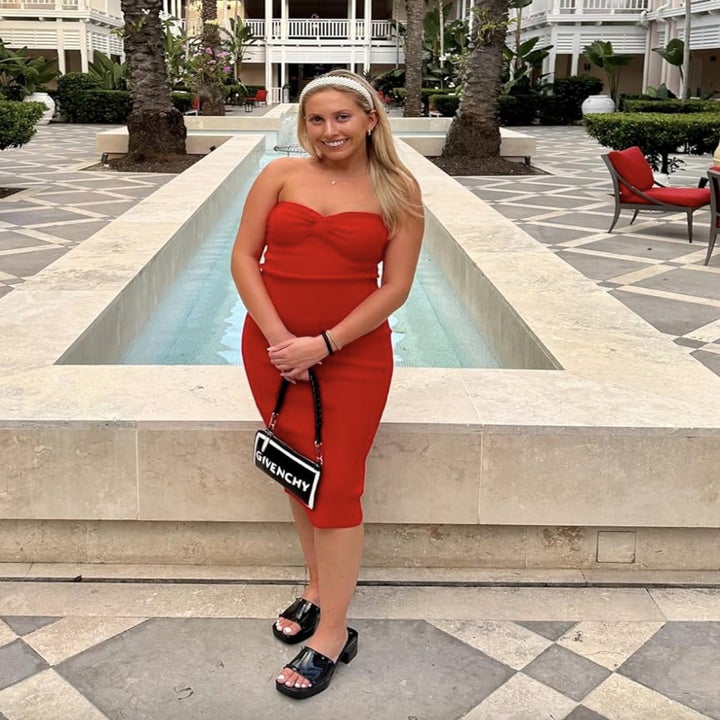 reviewer in strapless red dress with Givenchy bag standing by a pool
