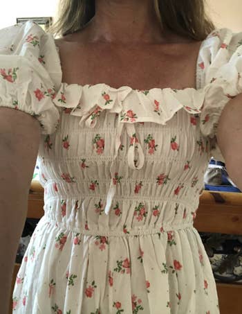 Person successful a floral formal with puff sleeves and ruffled neckline; photograph shows from cervix to waist