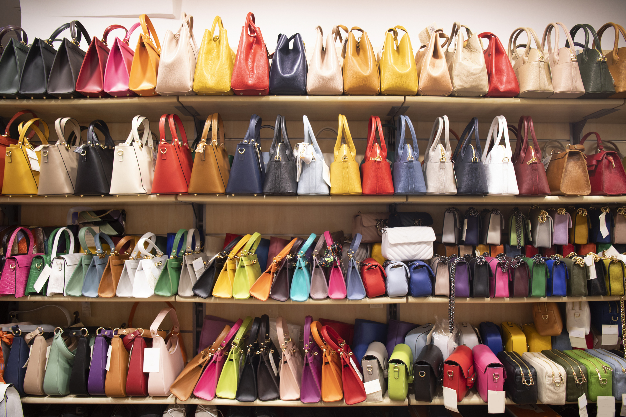 Shelves lined with a variety of handbags in multiple sizes and designs, displayed in a store setting