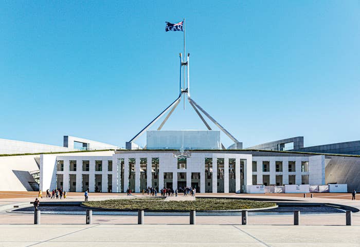 Australian Parliament House with visitors at entrance and flag above