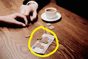 Two hands on a table, one with an engagement ring, near a coffee cup and coins highlighting the cost of a date