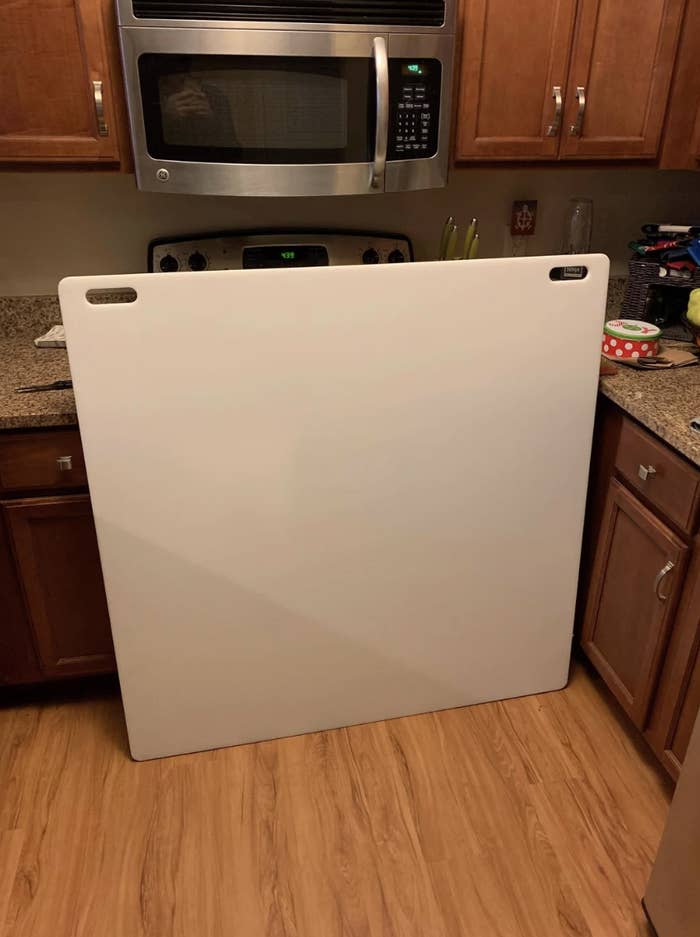 A large white board standing in a home kitchen with appliances and countertops visible in the background