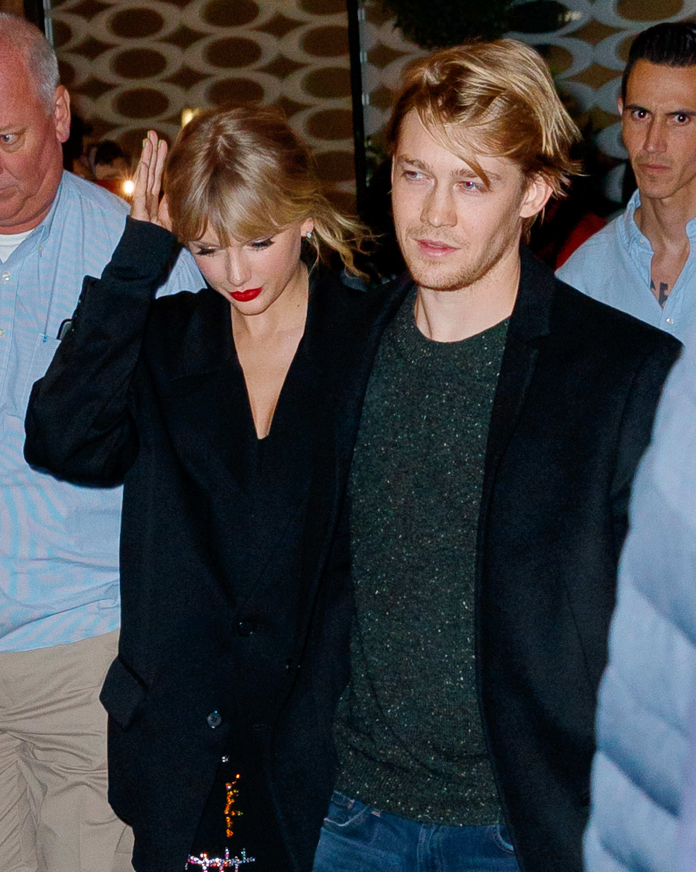 Taylor Swift in a black coat with Joe Alwyn wearing a green shirt and jacket, walking together