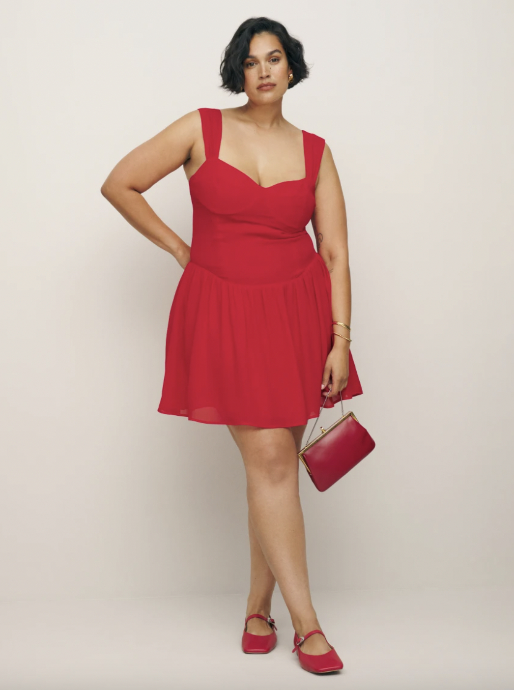 model in a sleeveless red dress with matching shoes and handbag, posing confidently