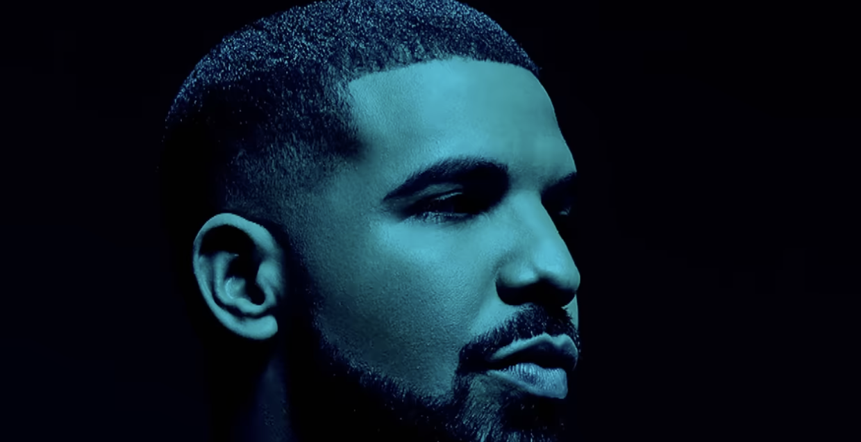 Drake with a contemplative expression in a dimly lit profile view