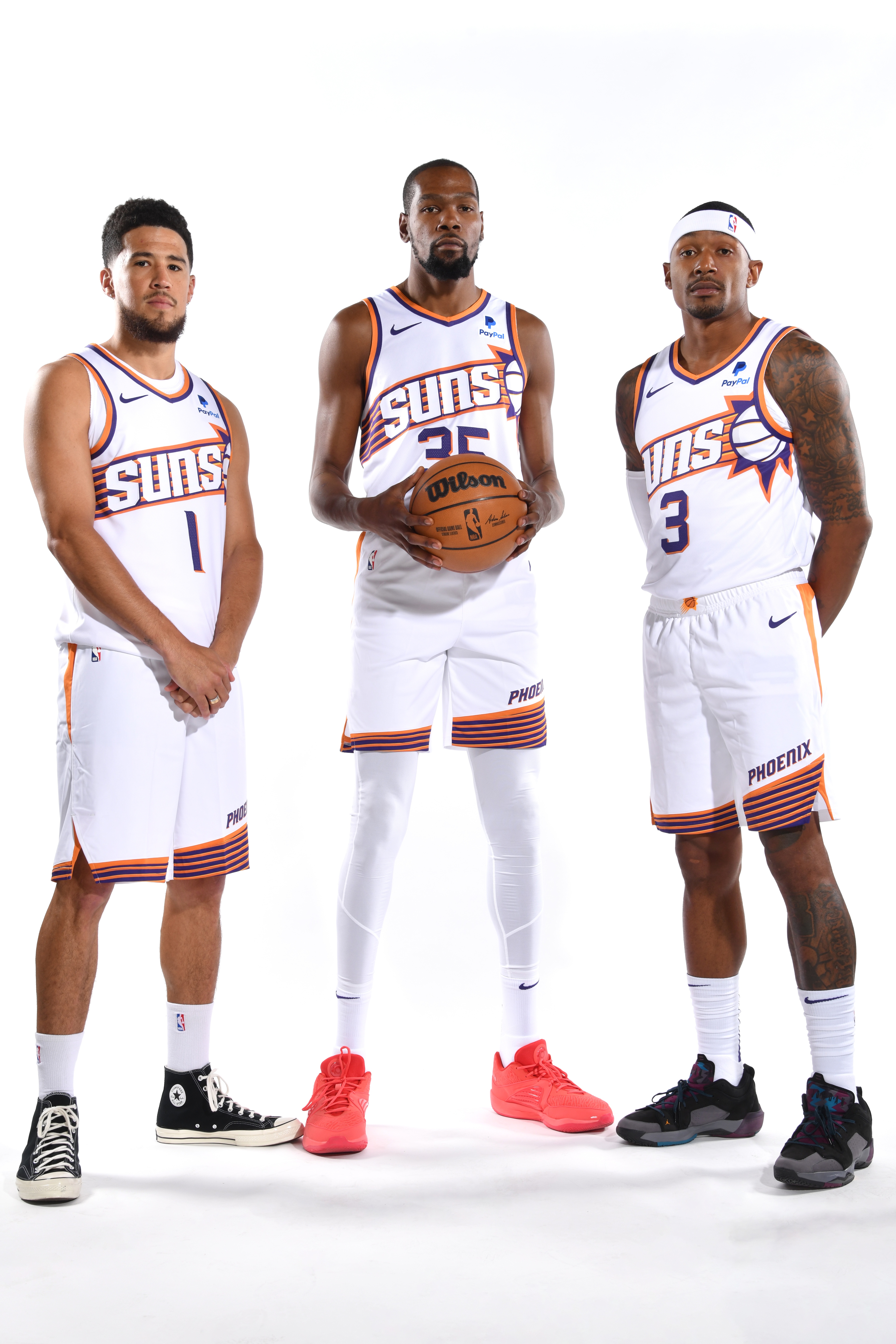 Three Phoenix Suns players standing side by side in white basketball uniforms