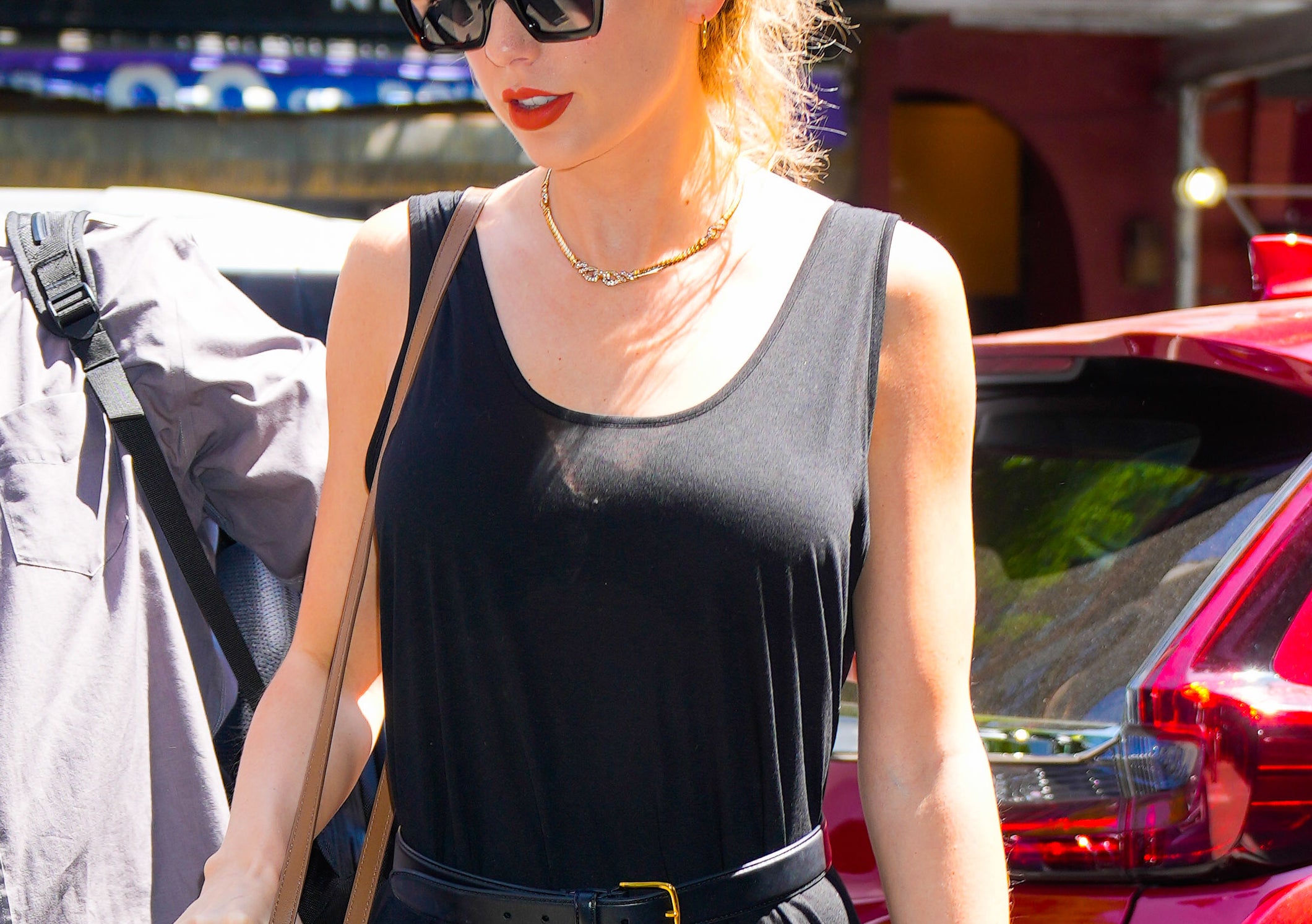 Taylor Swift walking outside in a sleeveless dress with sunglasses