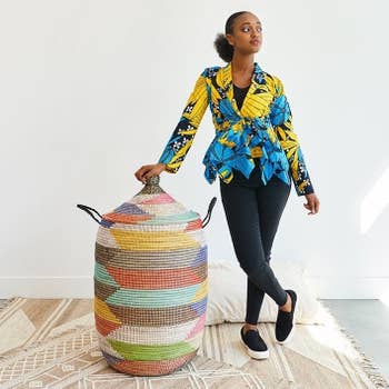 Woman successful patterned apical and jeans stands adjacent to a ample striped retention basket