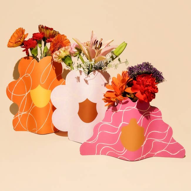 Three decorative look   vases with floral arrangements connected  a neutral background, showcasing a location  decor trend