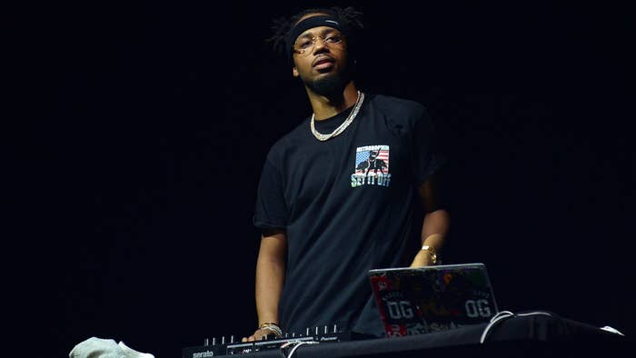 DJ performing on stage with a laptop and turntable setup