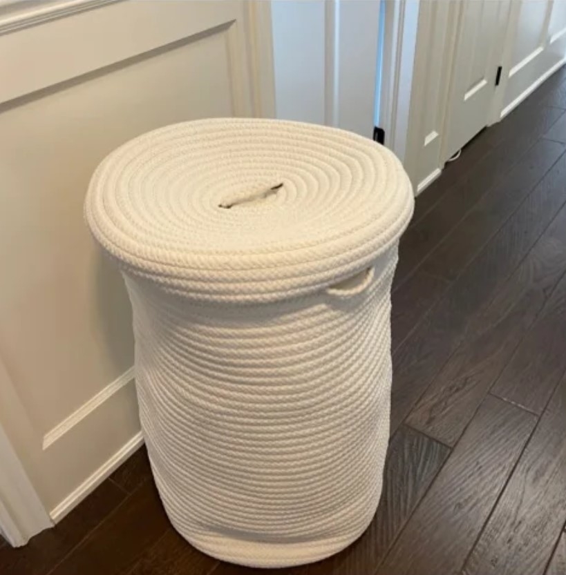 Reviewer&#x27;s photo of the woven laundry hamper in the color white with lid in a home setting