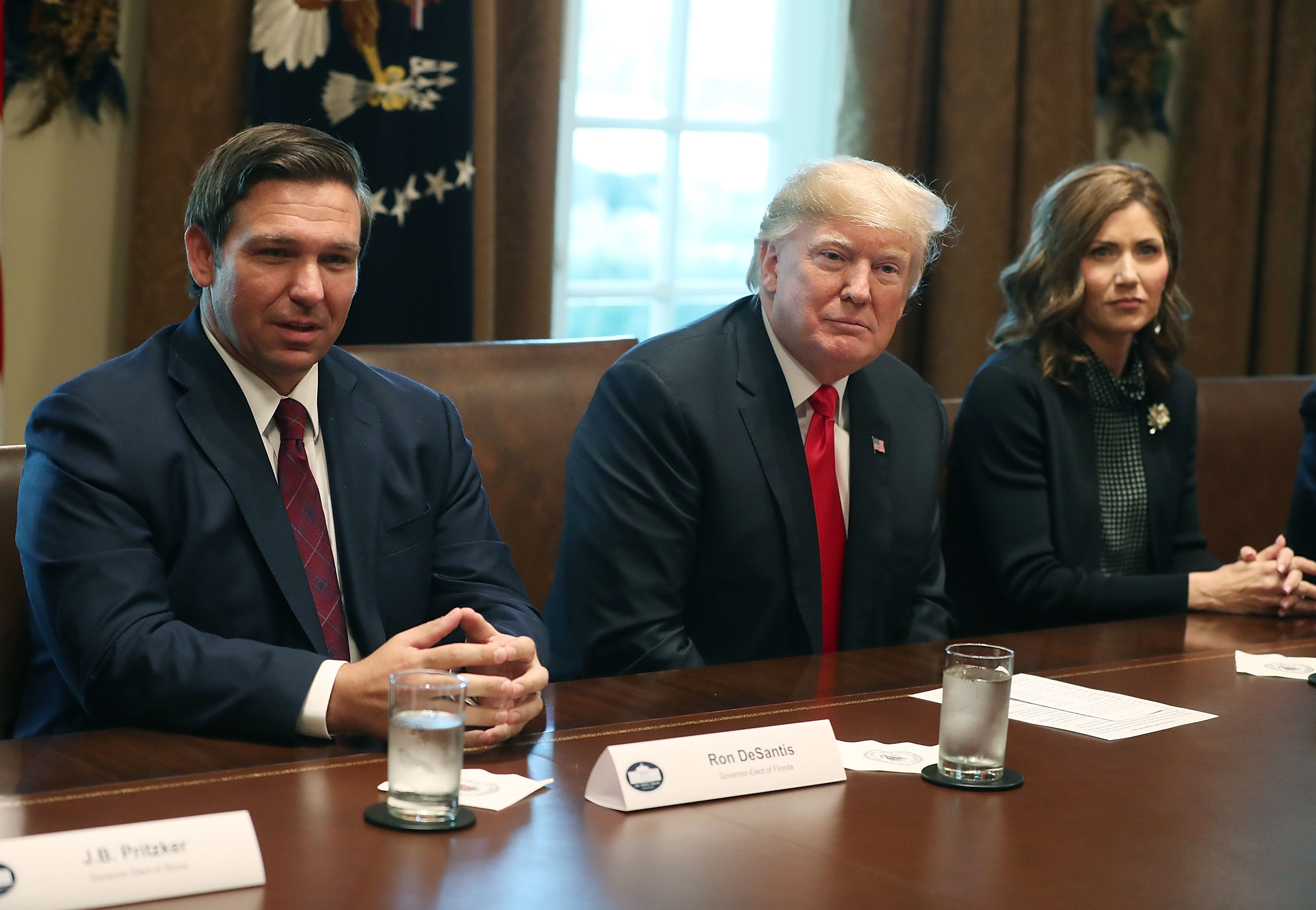 Ron DeSantis, Donald Trump, and Kristi Noem sitting at a conference table