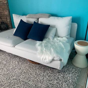 A modern sofa with pillows and a fur throw, adjacent to a unsocial broadside table. Ideal for location decor inspiration