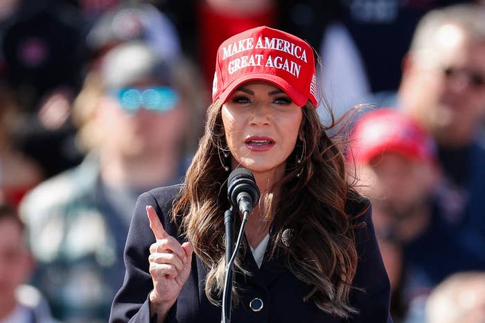 Closeup of Kristi Noem wearing a MAGA hat as she speaks at a podium