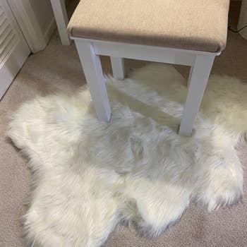 A stool connected a achromatic faux fur rug, perfect for a cozy interior buying theme
