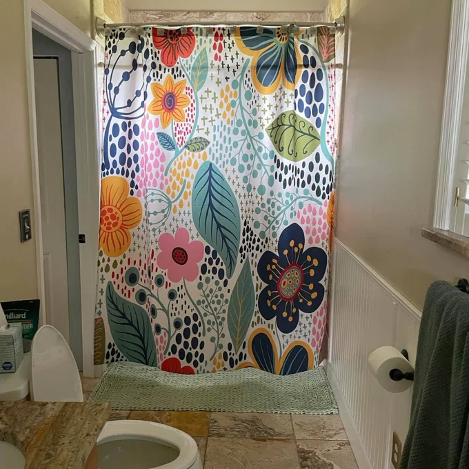 Reviewer&#x27;s photo of the vibrant floral pattern shower curtain inside a bathroom