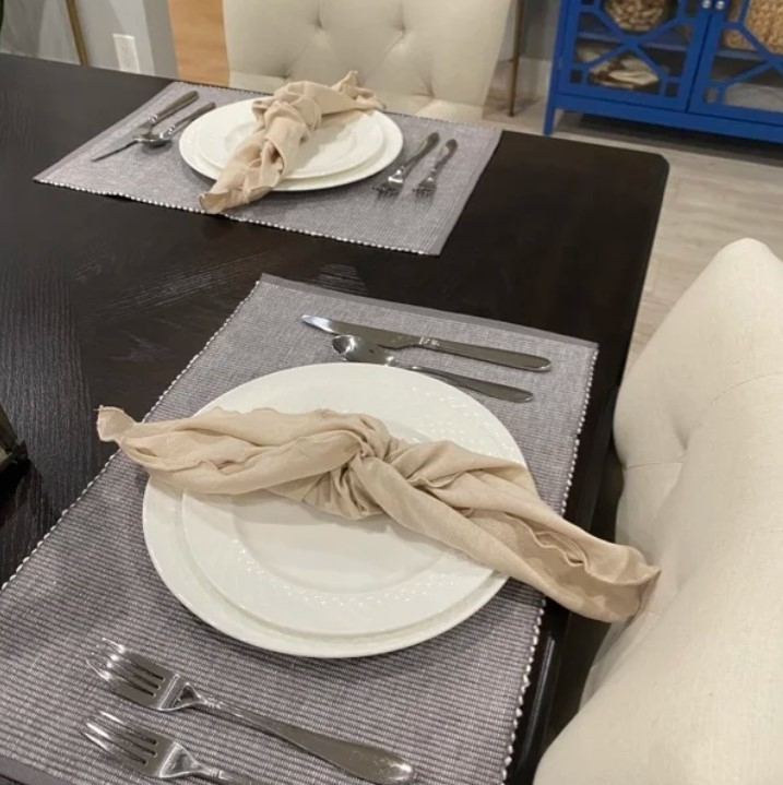 Reviewer&#x27;s photo of two table settings with the placemats, plus plates, napkins, and cutlery