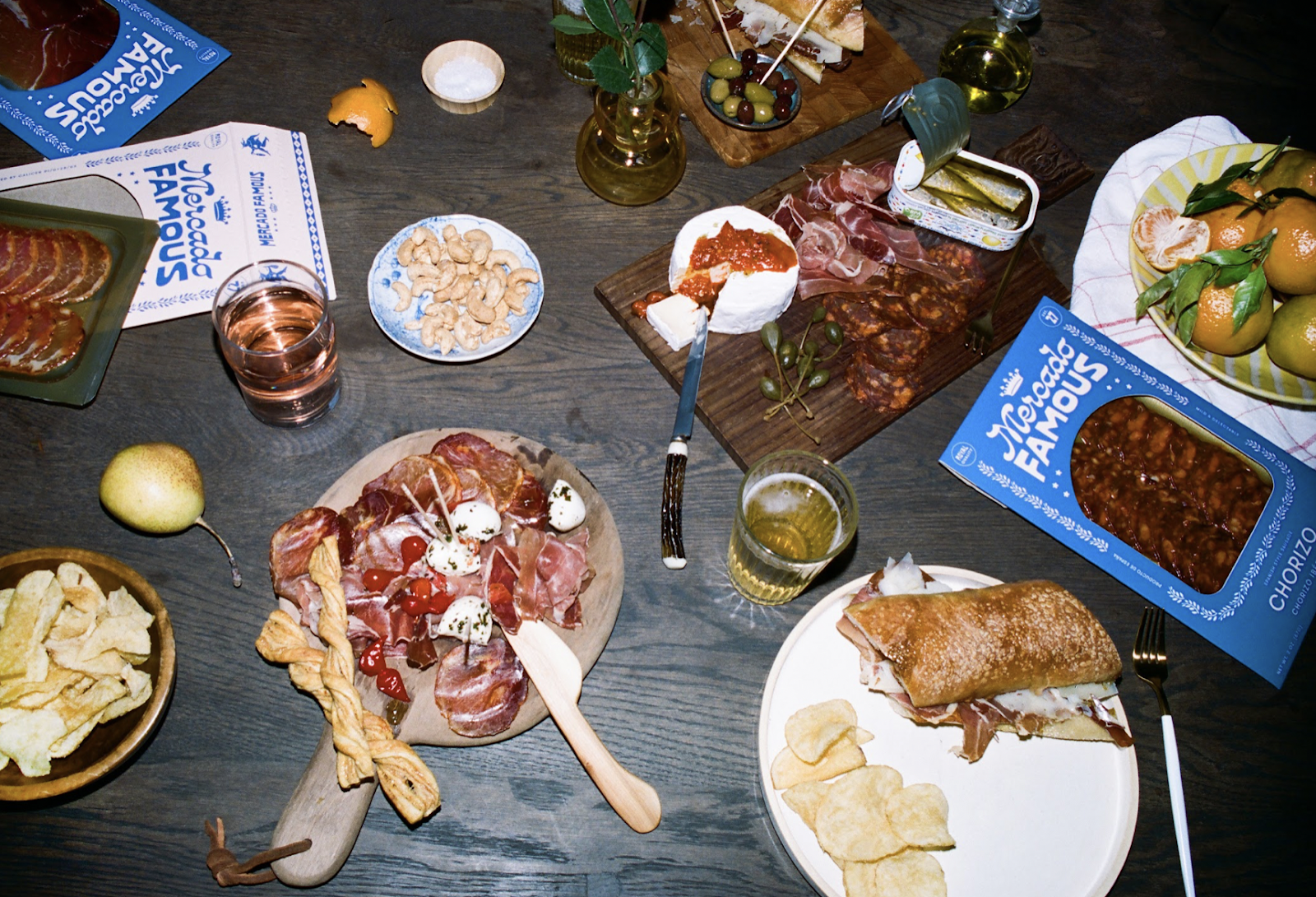 Overhead view of a table spread with various snacks, charcuterie, and two boxes of advertised products
