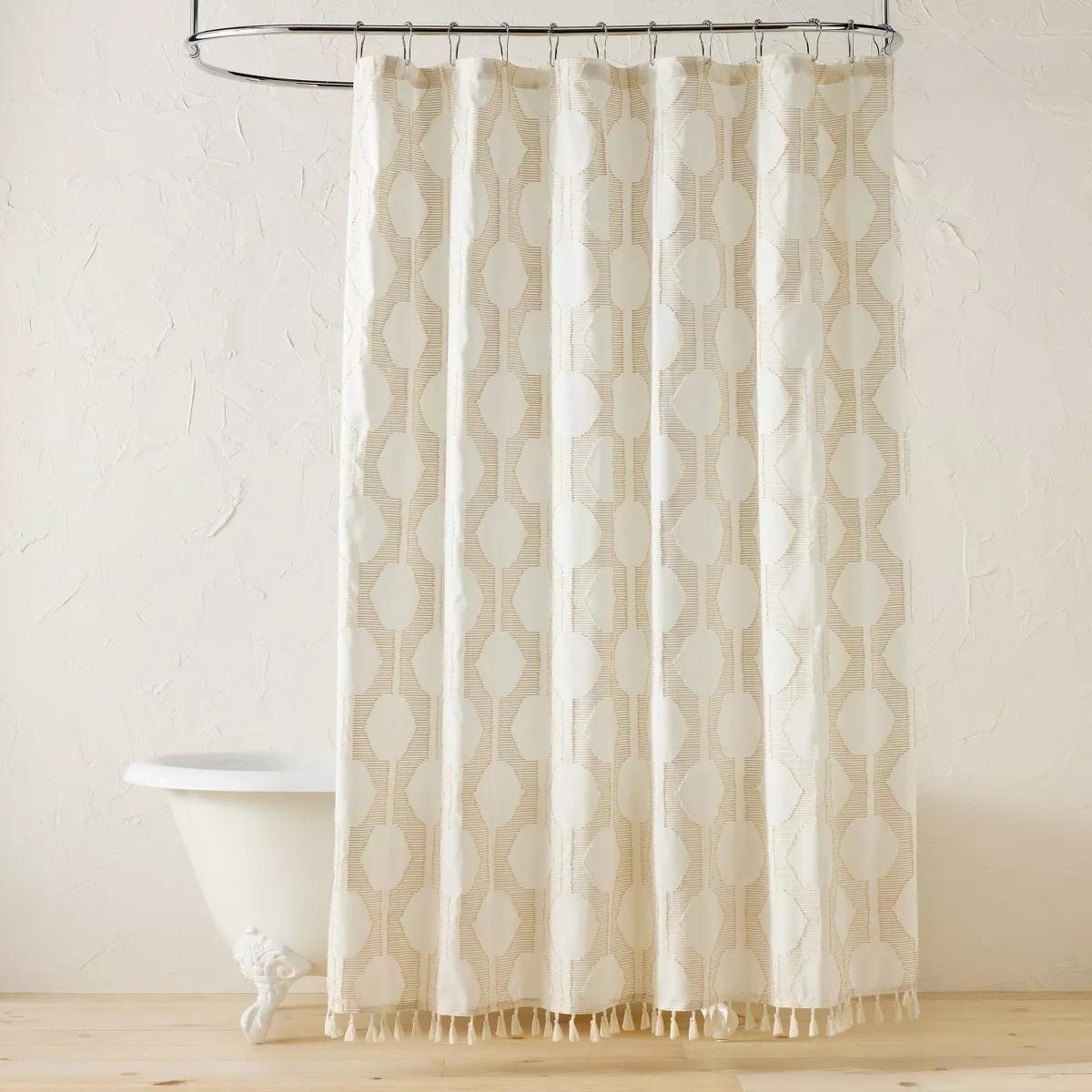 Shower curtain with geometric pattern and fringe displayed in a bathroom setting for a shopping article