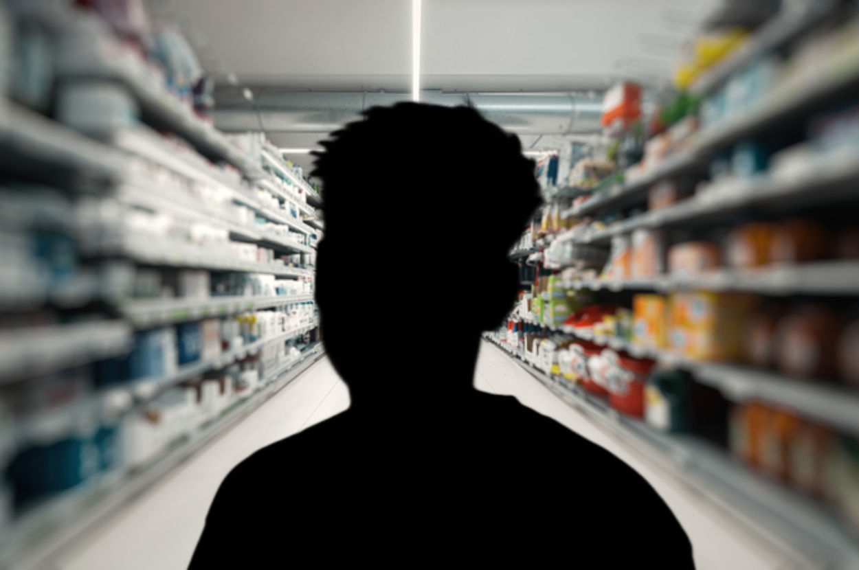 Silhouette of an unidentifiable person standing in a supermarket aisle