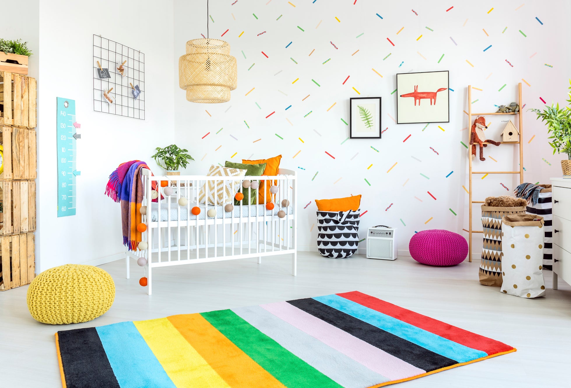 Colorful nursery room with a crib, storage shelves, and a rainbow-striped rug. No persons present