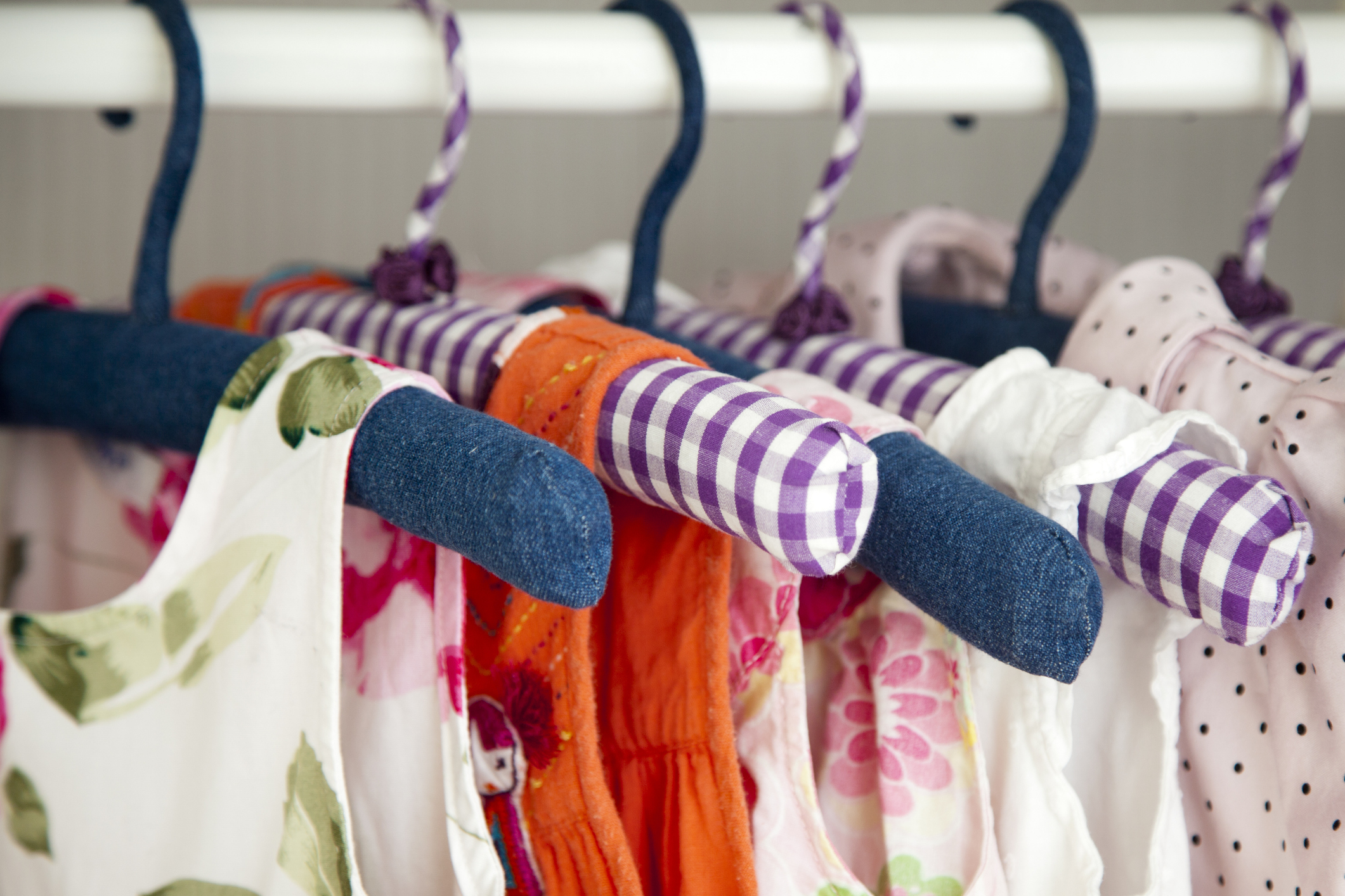 Children&#x27;s clothes on hangers, with various patterns and a blue sock hanging on one
