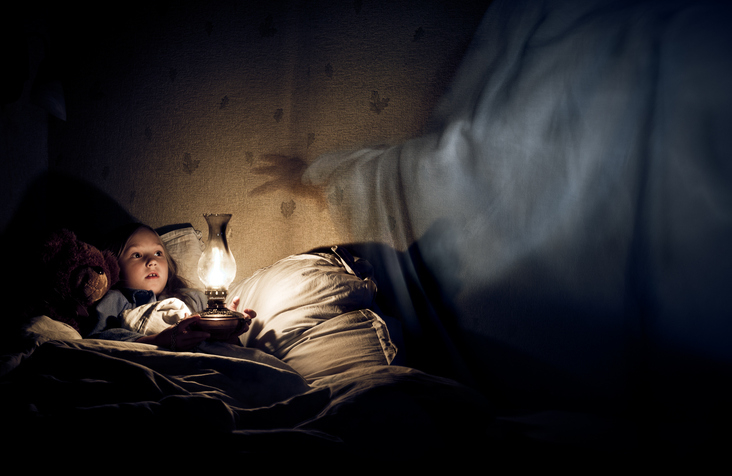 Child in bed looking at a glowing lantern, with a figure&#x27;s outstretched hand