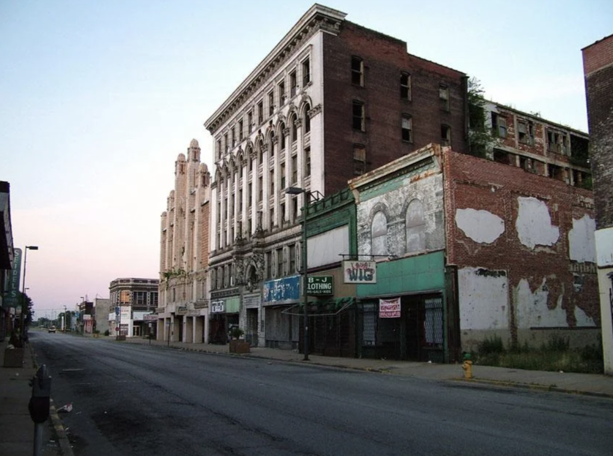 Row of dilapidated urban buildings with boarded-up storefronts on a deserted street