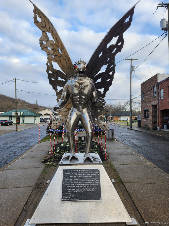 Statue of the Mothman, a legendary creature, displayed in a public space with a plaque at the base