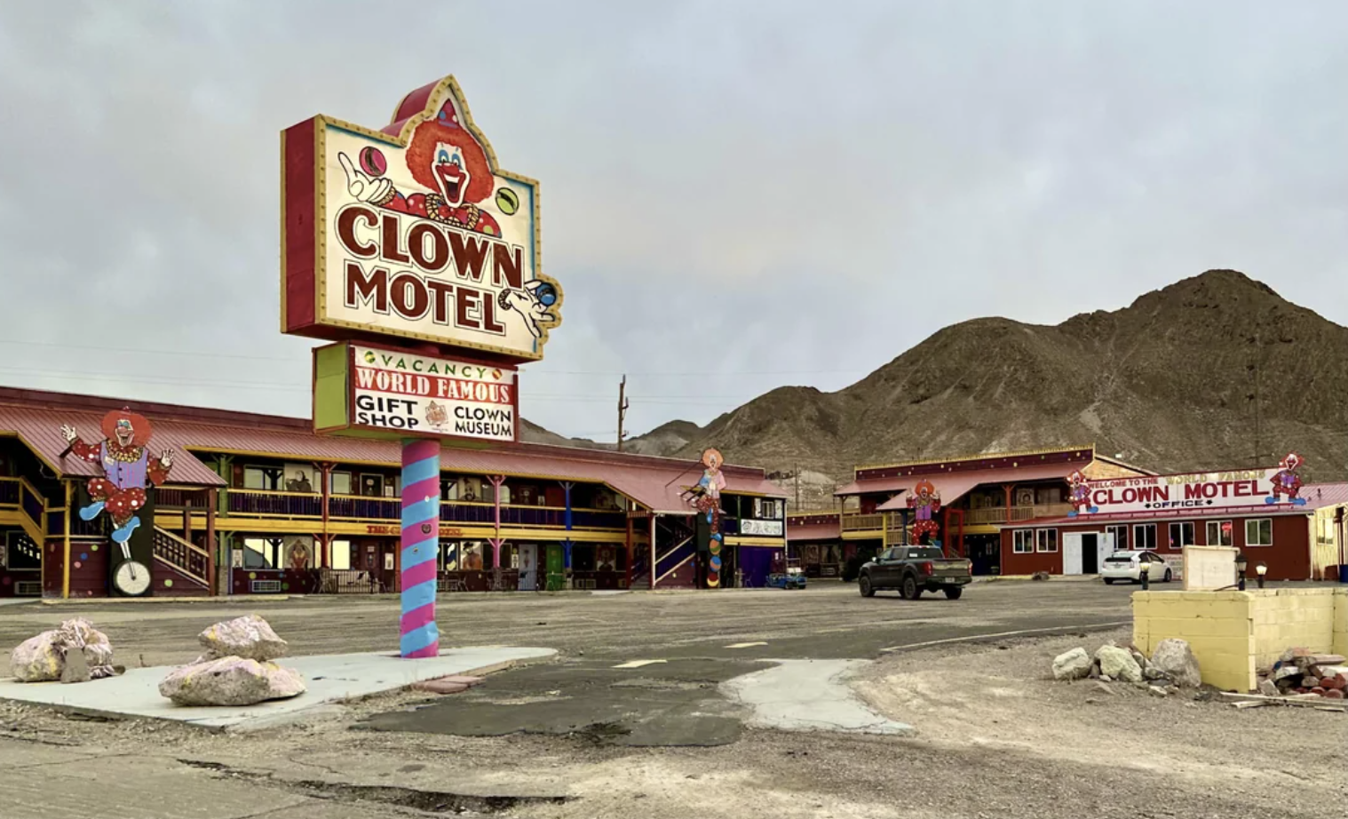 Clown-themed motel with large sign and clown figures outside; adjacent to a mountainous backdrop