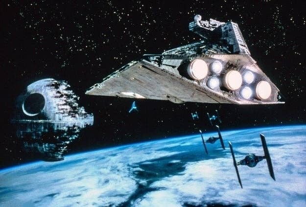 A Star Destroyer and Death Star orbit a planet with smaller spacecraft and stars in the background