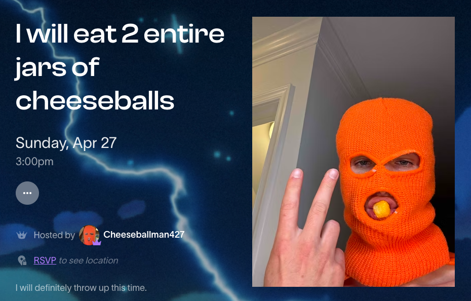 A person poses with an orange-knitted mask, with holes for eyes and mouth, where a cheeseball is placed. They are gesturing a &#x27;two&#x27; sign