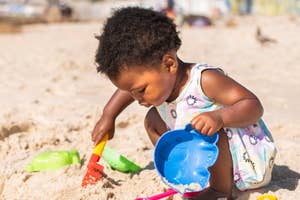 A toddler playing with beach toys in the sand