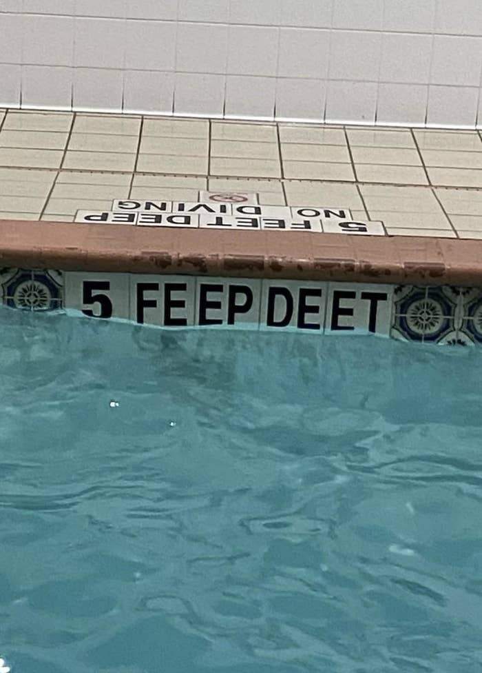 Swimming pool edge with misspelled "5 FEEP DEET" signage