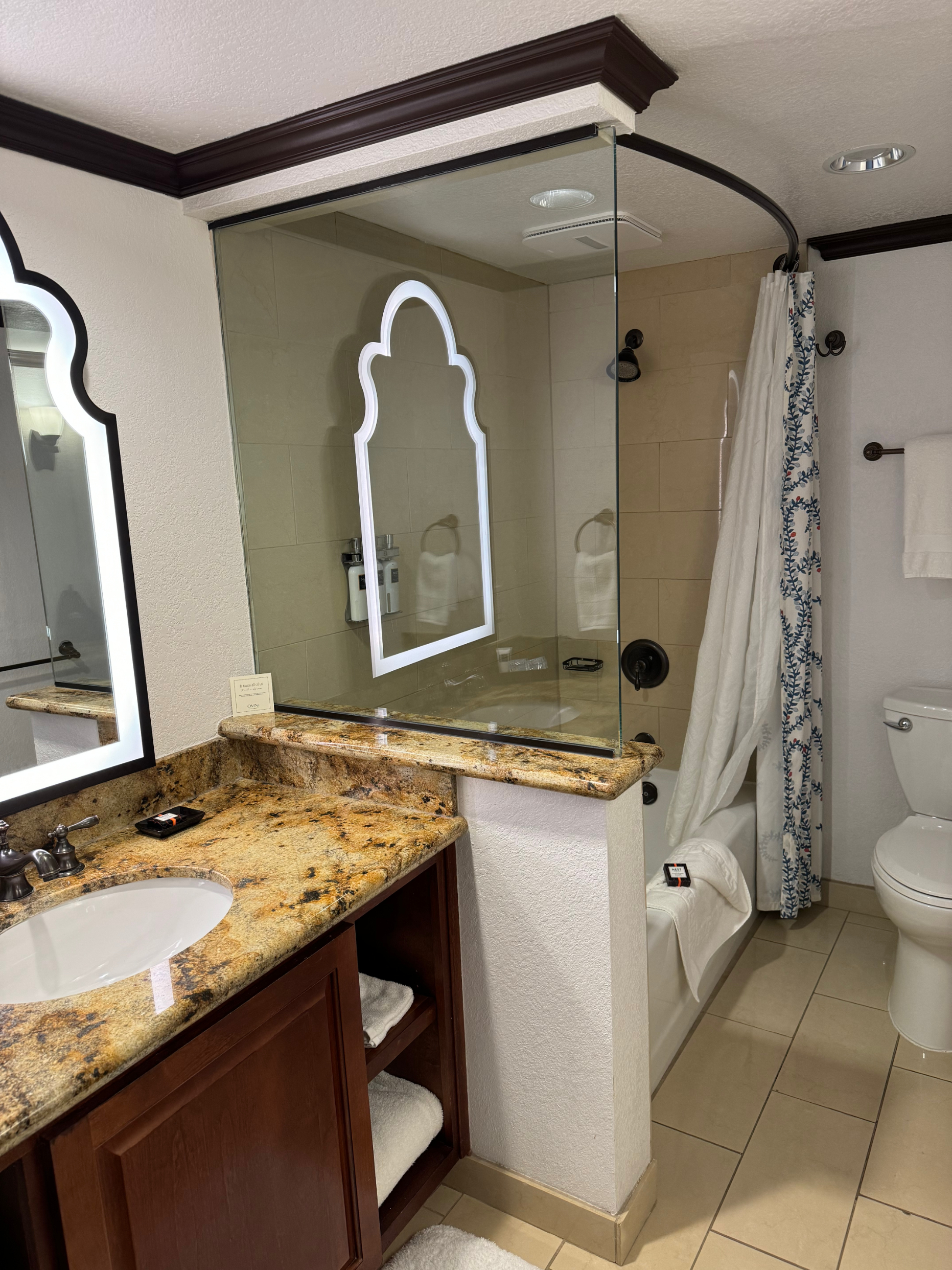 Hotel bathroom with a vanity area, shower stall, and reflective mirror. No people present