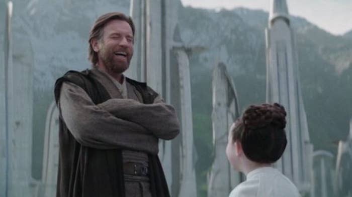 Two characters from &quot;Obi-Wan Kenobi&quot; series stand outdoors, one smiling broadly with crossed arms