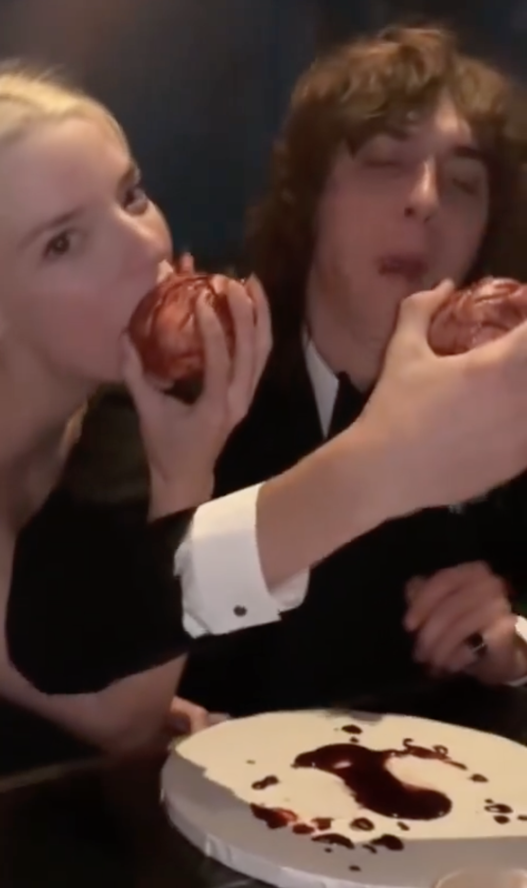 Two individuals playfully taking a bite from the same apple