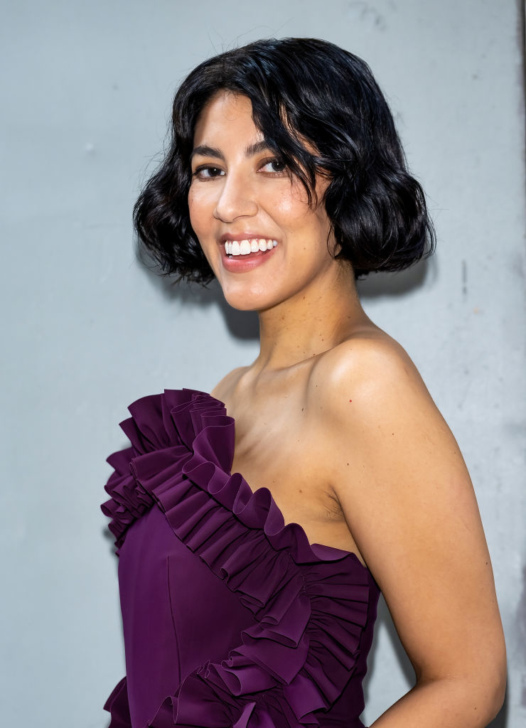 Stephanie Beatriz smiling in an elegant ruffled dress on a celebrity event