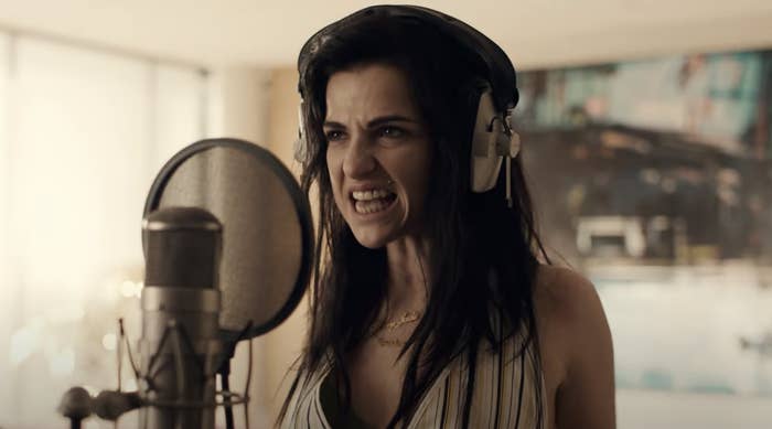 Marisa Abela as Amy Winehouse in a recording studio with headphones on, singing passionately into a microphone