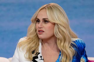 Rebel Wilson wearing a blazer with a lapel pin, with a serious expression