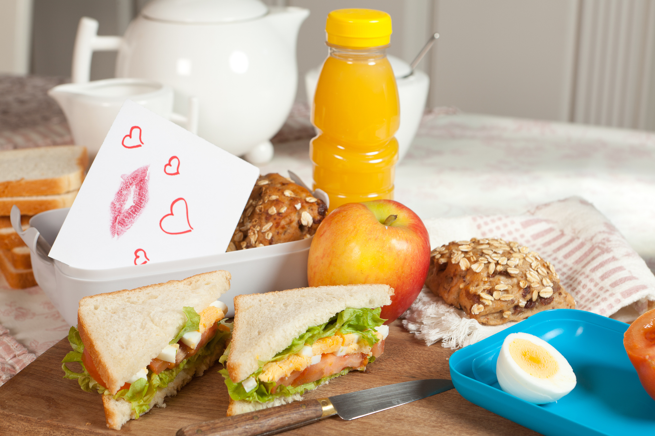 Healthy lunch spread with sandwiches, fruit, boiled egg, juice, and love note on the table