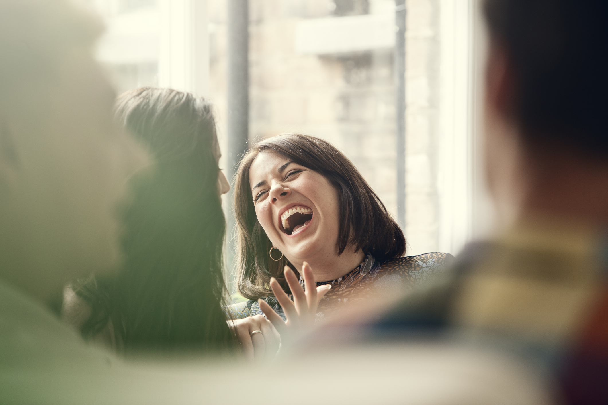 Woman laughing amidst a group, expressing joy in a social gathering