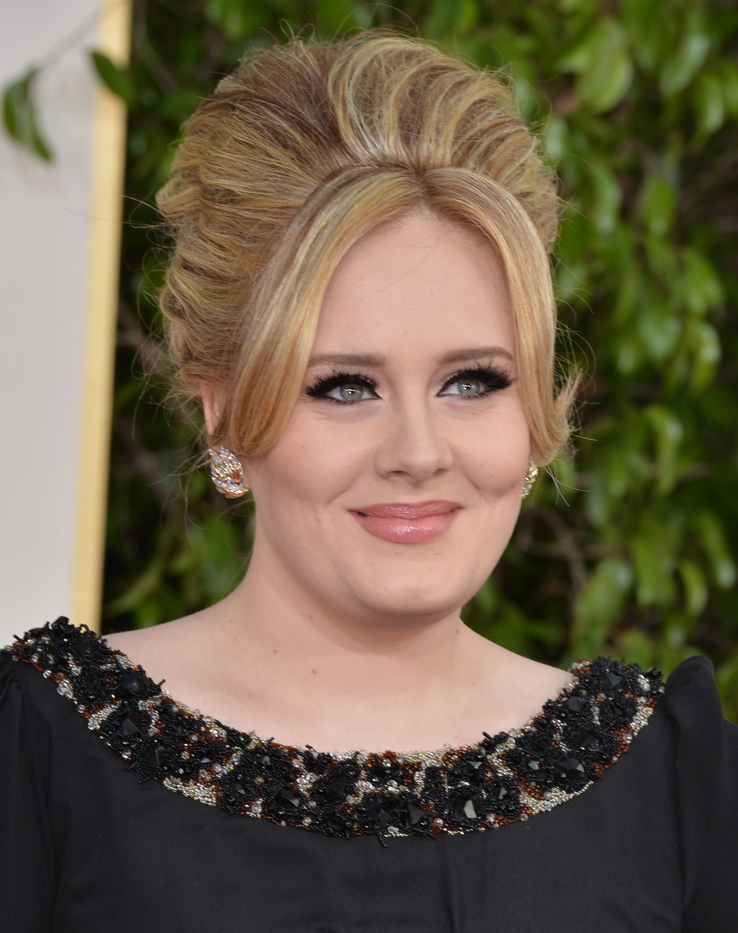 Adele smiling, wearing a embellished dress with an updo hairstyle at an event