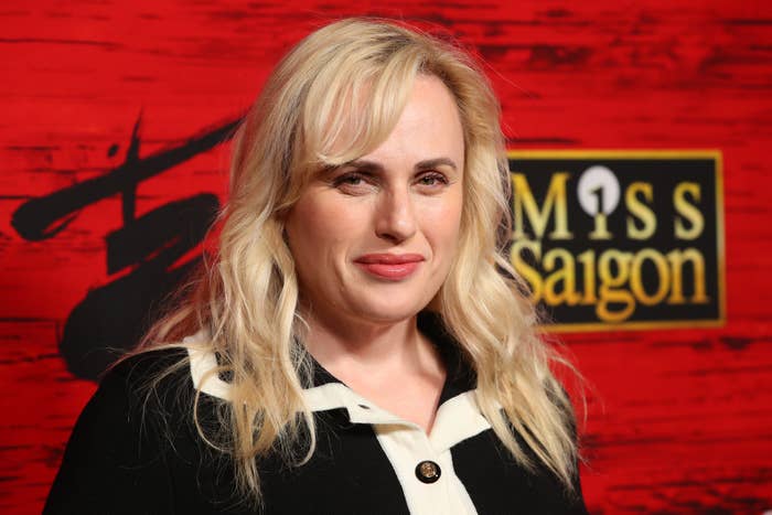 Rebel Wilson in a black and white outfit smiling at a Miss Saigon event
