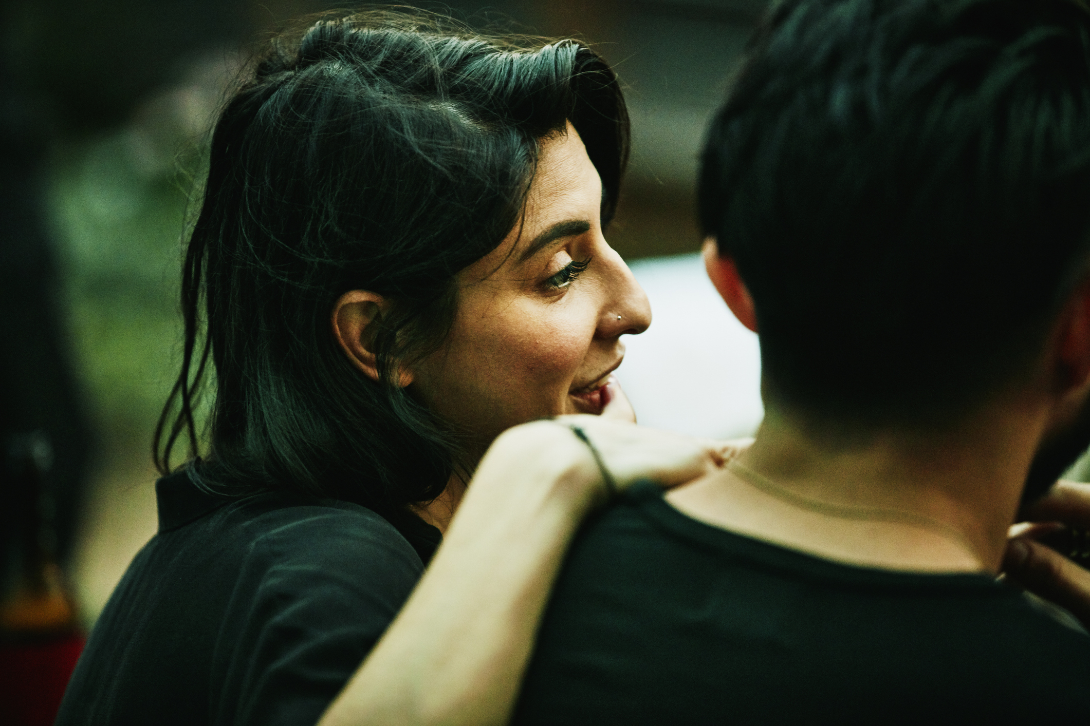 Two people in close conversation, one with shoulder-length hair facing away